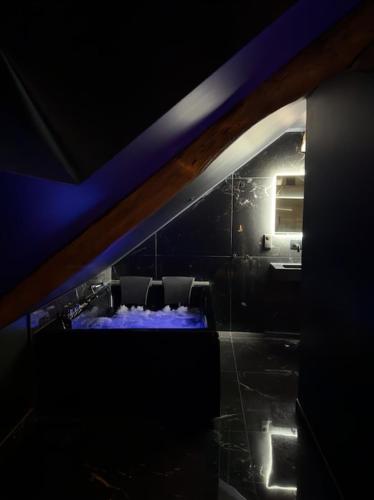 a dark room with a table and chairs in a room at BlackRoom - Balnéo - Ciel étoilé in Belfort