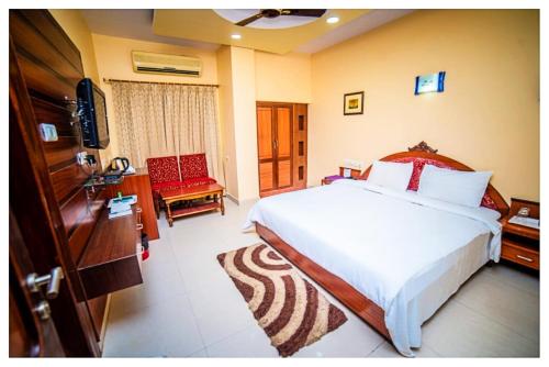 a bedroom with a bed and a television and a chair at Power Onn Grand Cuttack Residency in Cuttack