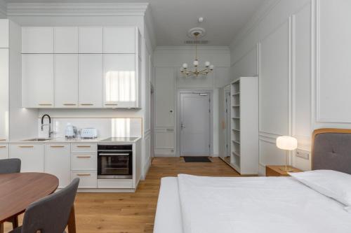 a white kitchen with a table and a bed at Roze Center Apartments in Liepāja