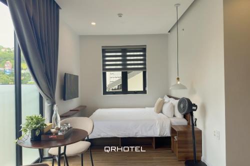 a bedroom with a bed and a table and a window at QR Hotel Dalat in Xuan An