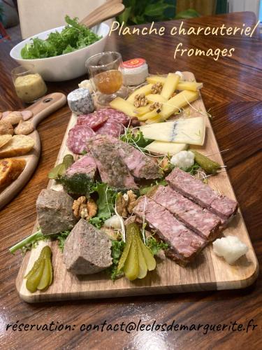 a cutting board with meat and cheese and other foods at Le Clos de Marguerite in Mellecey