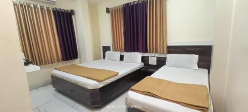 a room with two beds in it with curtains at Hotel Sai viraj palace in Shirdi