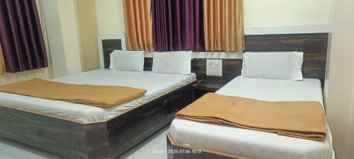 two twin beds in a room with curtains at Hotel Sai viraj palace in Shirdi