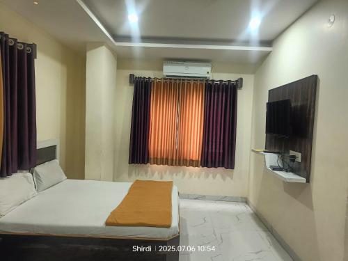 a bedroom with a bed and a television in it at Hotel Sai viraj palace in Shirdi