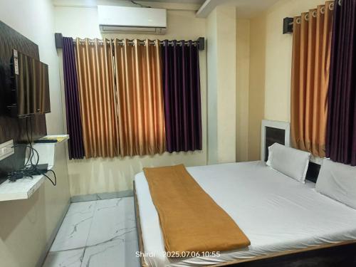 a bedroom with a bed and a window with curtains at Hotel Sai viraj palace in Shirdi