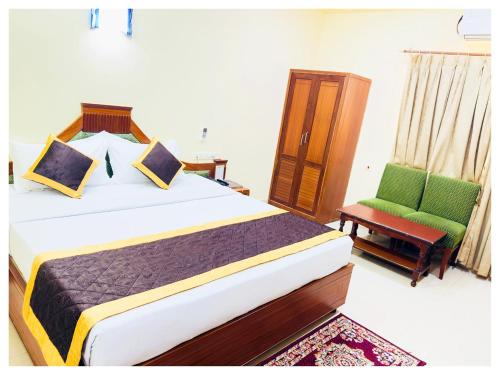 a bedroom with a bed and a green chair at Power Onn Grand Cuttack Residency in Cuttack