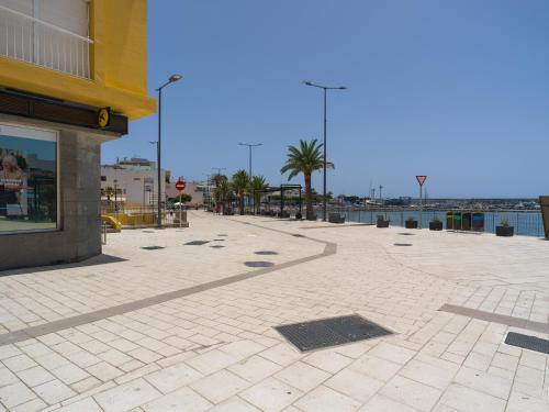 a empty sidewalk next to a building next to the water at Marañuelas Beach Suites Arguineguin in Arguineguín