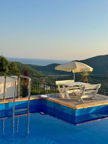 a pool with a picnic table and an umbrella at Kangaroo Apartmani in Prijevor