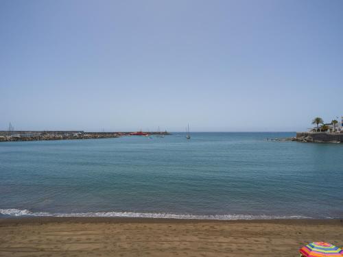 a beach with an umbrella and the ocean at Marañuelas Beach Suites Arguineguin in Arguineguín