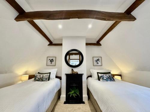 two beds in a room with a mirror at Rutland Cottage, Ketton, Stamford by Belmont Places in Ketton