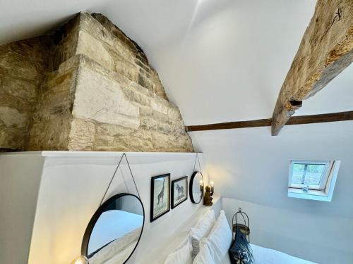a bedroom with a stone wall and a mirror at Rutland Cottage, Ketton, Stamford by Belmont Places in Ketton