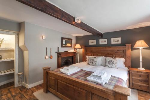 ein Schlafzimmer mit großem Bett und Kamin in der Unterkunft Three Little Pigs Luxury Cottage in Milton Abbas