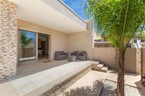 a patio with two chairs and a palm tree at Raksha House by BarbarHouse in Torre Pali 