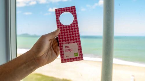 a person holding up a red and white napkin holder at Ibis Styles Macaé in Macaé