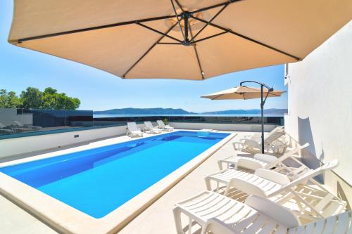 a swimming pool with white chairs and an umbrella at Apartmani Olimp2 in Sveti Juraj