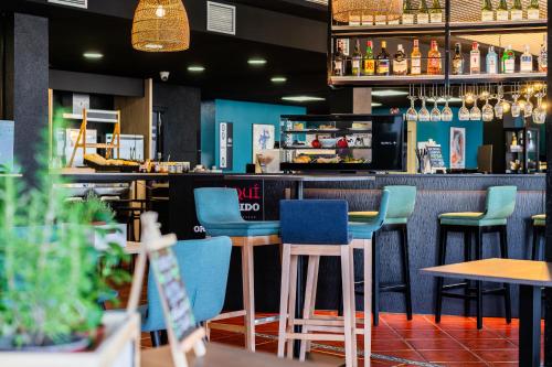 a bar with blue and green chairs in a restaurant at Ibis Jerez De La Frontera Cadiz in Jerez de la Frontera