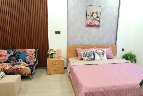 a bedroom with a pink bed and a couch at Andi Homestay-Vinhomes Grand Park in Gò Công