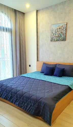 a bedroom with a large bed with blue sheets at Andi Homestay-Vinhomes Grand Park in Gò Công