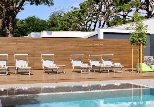 a row of lounge chairs next to a swimming pool at Hotel Mealba in Saronno