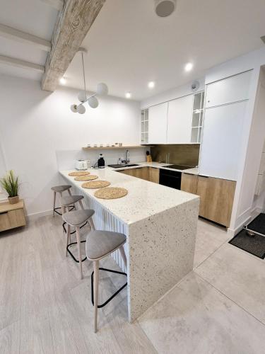 a kitchen with a white counter and stools at Pinea Apartments in Pobierowo