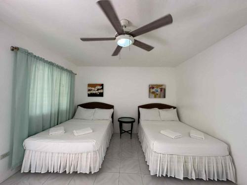 two beds in a room with a ceiling fan at Labros Adventure Camp and Waterfront in Calintaan