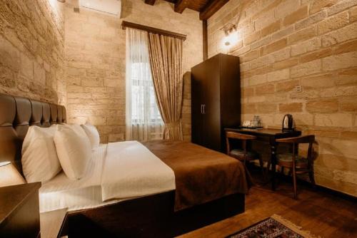 ein Schlafzimmer mit einem Bett und einem Schreibtisch darin in der Unterkunft Sazeli Old Baku Hotel in Baku
