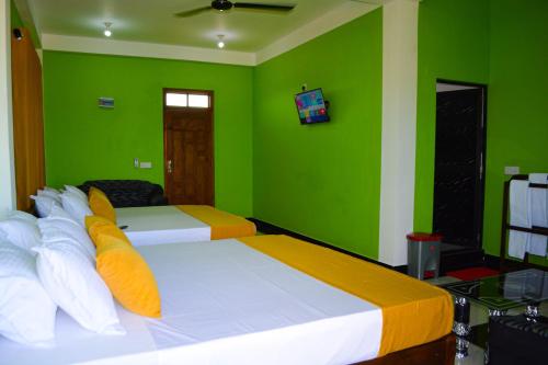 a green bedroom with two beds and a television at Luxury Everest Hotel in Trincomalee