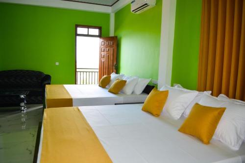 a green room with two beds with yellow and white pillows at Luxury Everest Hotel in Trincomalee