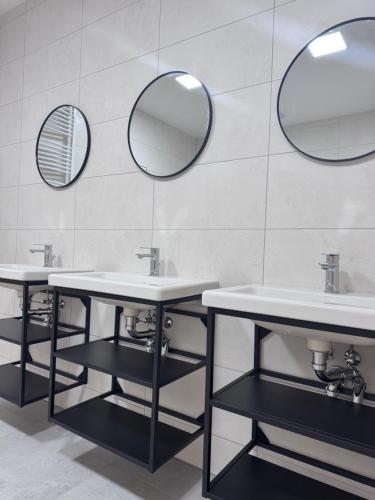 a bathroom with three sinks and two mirrors at Rybka living apartments in Přerov