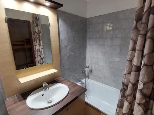 une salle de bain avec un lavabo, un miroir et une baignoire dans l'établissement Studio 28m² avec balcon, couchages pour 4, Wifi et parking, proche centre-village et thermes - FR-1-512-219, à Brides-les-Bains