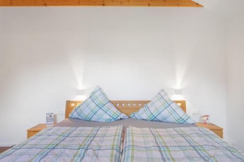 a bed with two blue pillows on top of it at Müllerjörgenhof in Gutach
