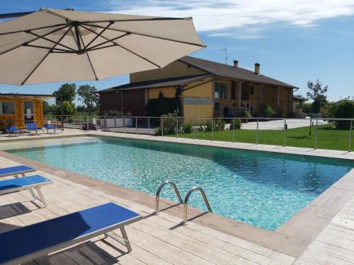 a swimming pool with an umbrella and a house at Cascina Olmetto di Sotto in Ghedi