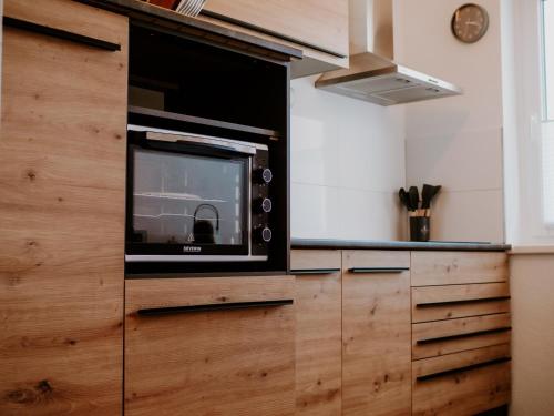 a microwave oven sitting on top of a wooden cabinet at Wohlfühlapartment, Parkplatz, Boxspringbetten, Massagesessel, Nespresso, 1Gbit LAN & WIFI, Innenstadt in Wolfsburg