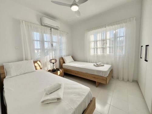 STAY Cavo Bay Villa في بروتاراس: غرفة نوم بسريرين ونوافذ