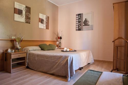 Habitación con cama, mesa y cuadros en la pared. en Hotel Adriano, en Turín