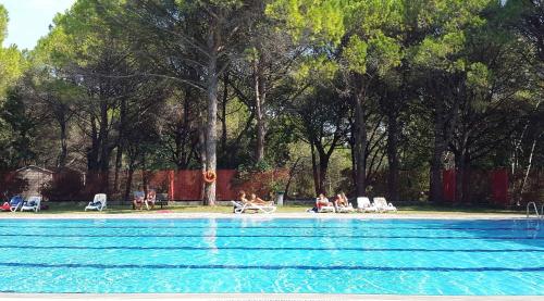 a group of people sitting in lawn chairs near a swimming pool at Houses and Mobilehomes in Grado 38490 in Grado
