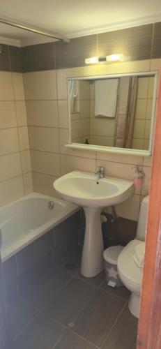 a bathroom with a sink and a toilet and a mirror at GLIPTIS Apartments in Karfas