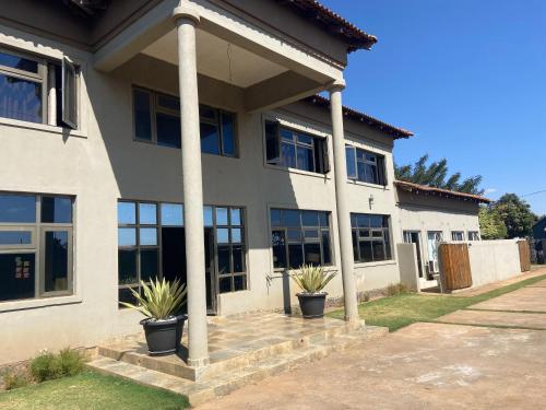Una casa con grandes ventanales y plantas en macetas delante de ella. en The Shed Venue & Boutique Hotel, en Lilongwe