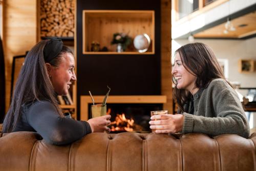 two women sitting on a couch with drinks at Hotel Li Anta Rossa - Adults Only in Livigno