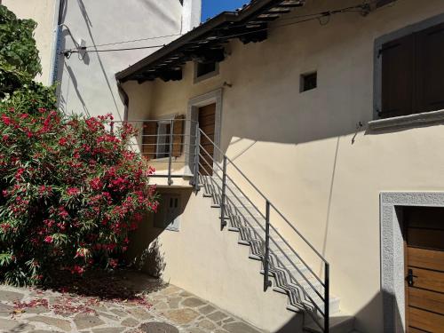 a white building with stairs and a bush with pink flowers at SMARTnoOK Rooms and Apartment in Šmartno