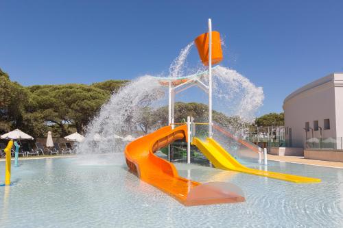 a water slide in a swimming pool with a fountain at Hipotels Barrosa Park in Chiclana de la Frontera