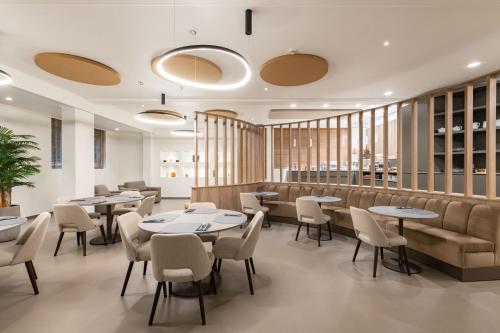 a restaurant with tables and chairs in a room at Hotel Mealba in Saronno