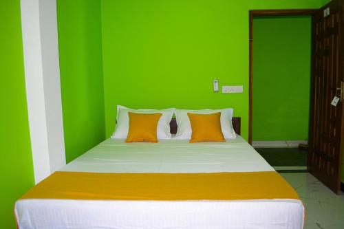 a green bedroom with a large bed with orange pillows at Luxury Everest Hotel in Trincomalee