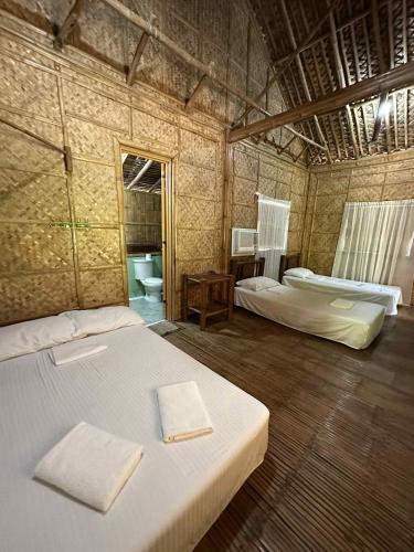 a large room with two beds and a bathroom at Labros Adventure Camp and Waterfront in Calintaan