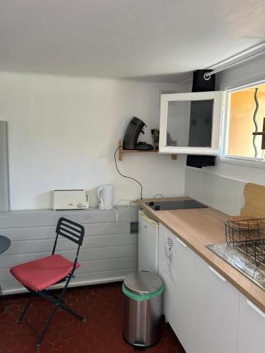 une petite cuisine avec une chaise rouge et un comptoir dans l'établissement La farigoulette, à Rayol-Canadel-sur-Mer