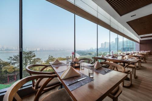a restaurant with tables and chairs and large windows at Chongqing Jiayu Emperor Hotel in Jiulongpo