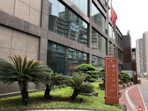 a sign in front of a building with palm trees at Chongqing Jiayu Emperor Hotel in Jiulongpo