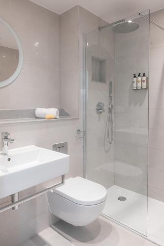 a white bathroom with a toilet and a shower at Harbour Hotel & Spa Brighton in Brighton & Hove