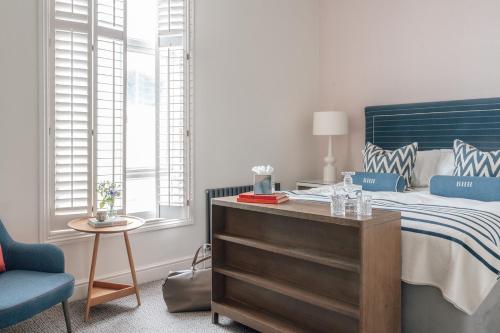 a bedroom with a bed with a blue headboard and a table at Harbour Hotel & Spa Brighton in Brighton & Hove