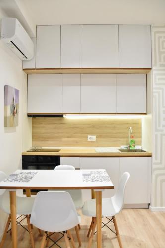 una cucina con mobili bianchi, tavolo e sedie di Wavefront Apartment 3 a Vlorë